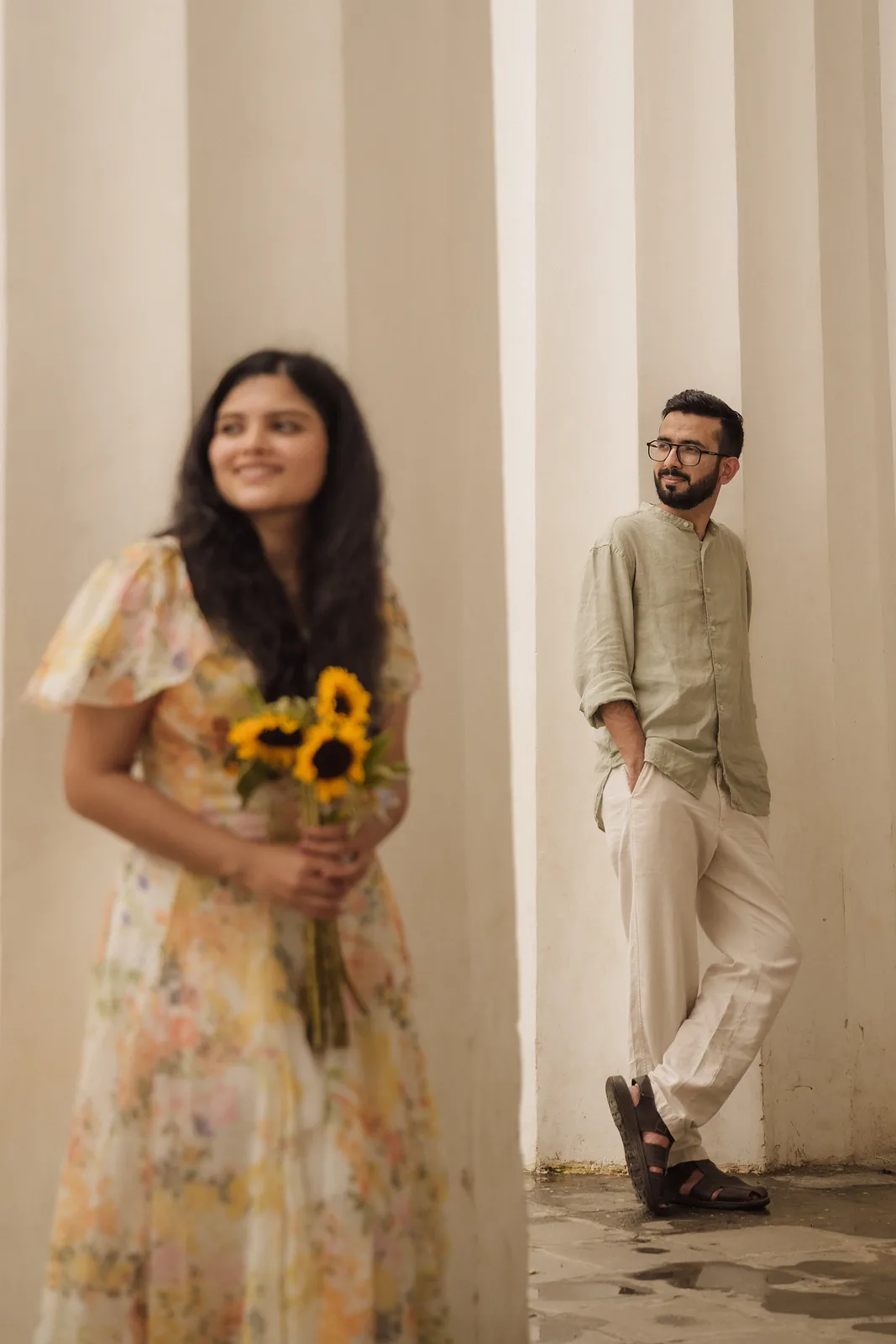 Manasi with sunflowers, Yash leaning on a column