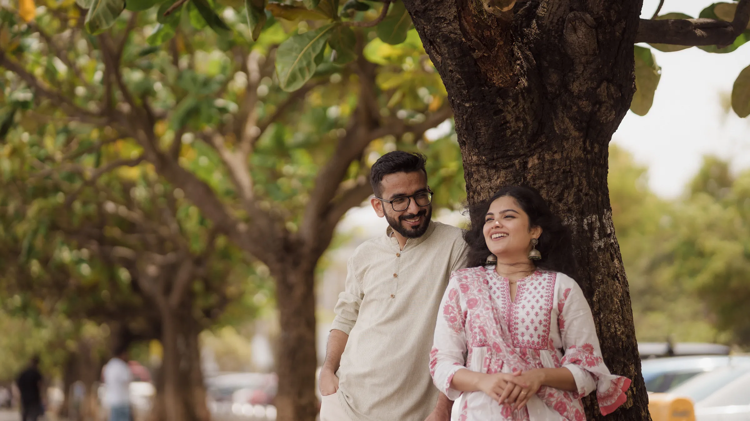 Yash and Manasi laughing beneath a tree